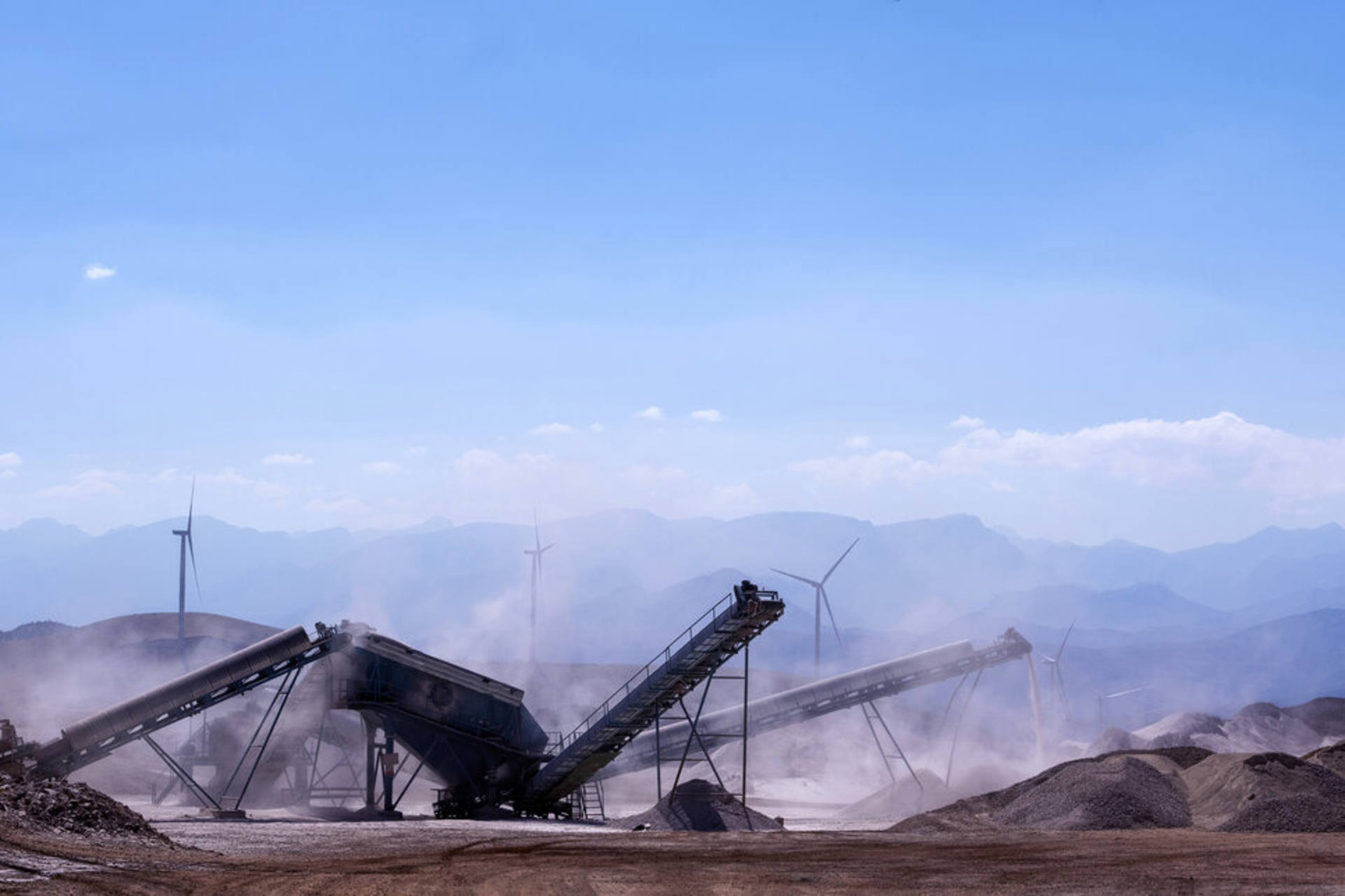 A substantial gravel pile set against a backdrop of towering mountains, showcasing a natural landscape.